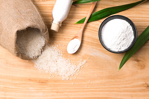 rice in hemp sack bag and white rice flour in wooden bowl