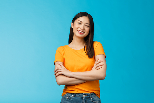 Cheerful friendly asian woman with dark short haircut smiling broadly enthusiastic conversation, talking you casually, cross arms chest confident pose, laughing carefree, stand blue background.