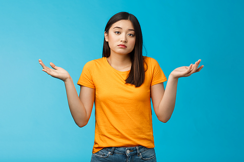 Shit happens. Indifferent absolutely careless female student not care how accident happened shrugging, look camera questioned unaware, hard answer, clueless how deal situation, stand blue background.