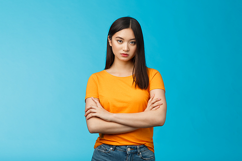 Serious-looking confident and arrogant asian woman cross hands chest powerful ignorant pose, look indifferent strict bored face, stand blue background unimpressed, demand answers. Copy space