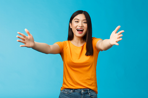 Come closer let me hug you. Cheerful lovely asian brunette girl stretch hands forward wanna cuddle, embracing friend smiling broadly inviting dear guests welcoming, stand blue background.