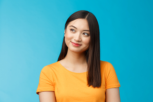 Close-up dreamy hopeful charming young asian woman wear yellow t-shirt turn sideways smiling delighted, contemplate beautiful summer scenery outside window sit office carefree, blue background.