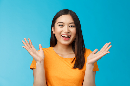 Close-up friendly happy cute asian female student clap hands joyfully, smiling broadly looking funny amusing performance, stand enthusiastic blue background applause surprised. Copy space