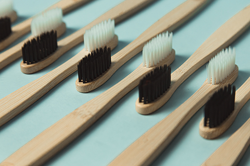 A close up of a minimalistic and repetitive patron of a lot of bamboo toothbrush over a clear blue background