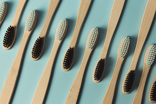 A close up of a minimalistic and repetitive patron of a lot of bamboo toothbrush over a clear blue background