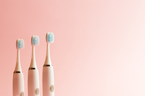 Conceptual shot of electrical toothbrush over a pink pastel background with copy space