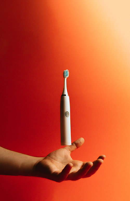 Conceptual shot of electrical toothbrush over a pink pastel background with copy space