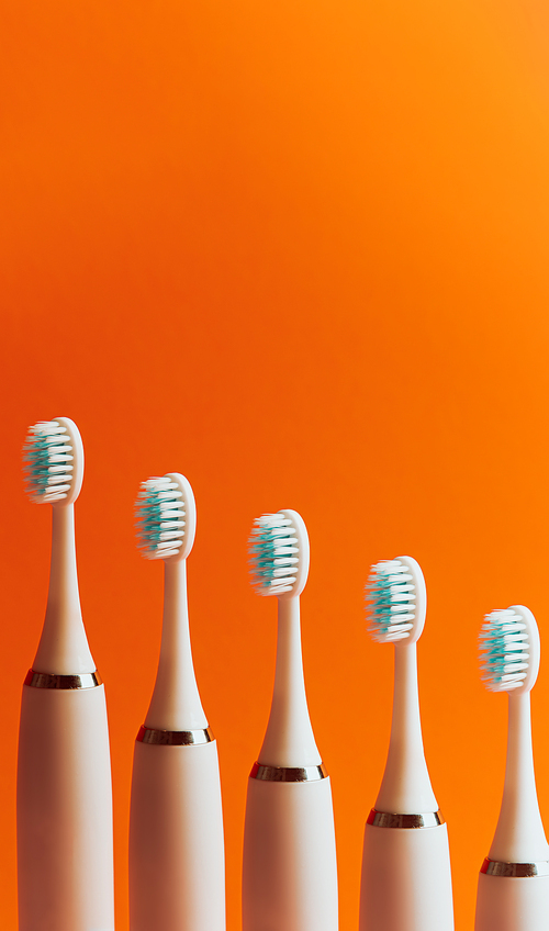 Conceptual shot of electrical toothbrush over a orange background with copy space