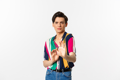 Scared and timid gay man asking to stop, looking alarmed and frightened, saying no, refusing or declining something, standing over white background.