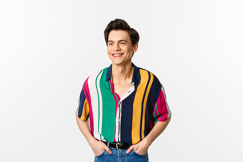 Image of handsome young man in colored summer shirt looking happy, standing over white background.