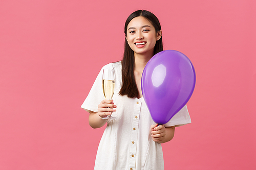 Celebration, party holidays and fun concept. Tender pretty asian woman in white dress, holding balloon and glass champagne, making toast during event, enjoying moment, pink background.