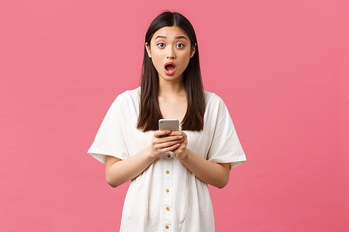 Beauty, people emotions and technology concept. Speechless and astonished asian girl react to big news, super big promotion, read something online using smartphone and stare at camera.