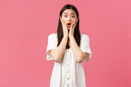 Beauty, people emotions and summer leisure concept. Shocked and concerned asian girl in white dress, gasping astonished, hear bad news, looking worried, standing pink background.