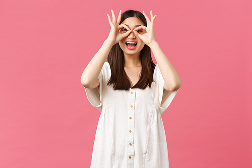 Beauty, people emotions and summer leisure concept. Playful gorgeous funny asian girl in white dress, make fake glasses from hands and looking through it at super cool promo, smiling amazed.