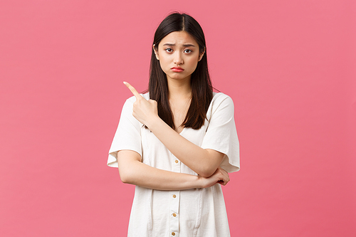 Beauty, people emotions and summer leisure concept. Upset gloomy girl in white dress, sulking and frowning as pointing upper left corner at bad news, disappointing advertisement banner.