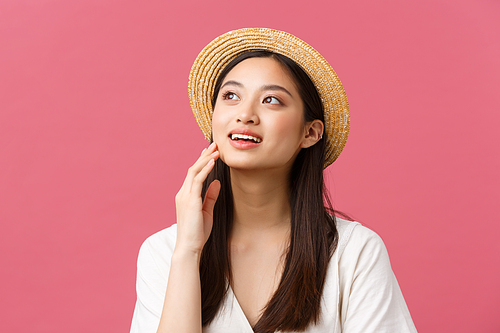 Beauty, people emotions and summer leisure and vacation concept. Dreamy tender, romantic asian woman in straw hat and white dress, looking upper left corner and gently touch face.