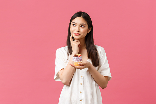 Food, cafe and restaurants, summer lifestyle concept. Thoughtful cute hesitant asian woman looking away doubtful, thinking about calories as staying on diet, tempting to eat delicious dessert.