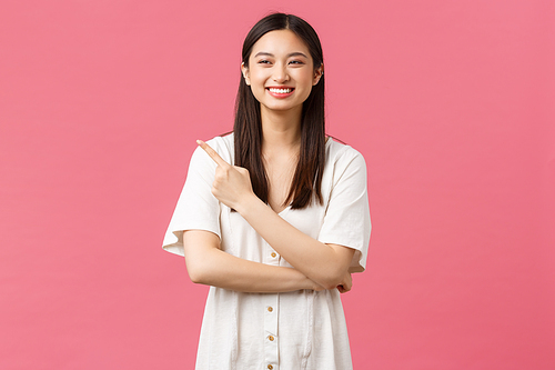 Beauty, people emotions and summer leisure concept. Attractive happy asian girl in cute dress, pointing finger upper left corner and laughing as advertising product or shopping mall promo offer.