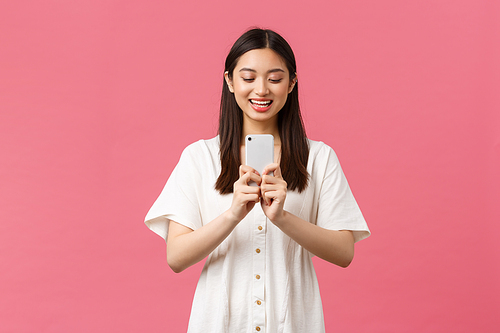 Beauty, people emotions and technology concept. Smiling happy asian female blogger, stylish girl taking photo on smartphone, looking upbeat as photographing, taking picture with mobile phone.