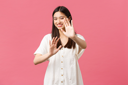 Beauty, people emotions and summer leisure and vacation concept. Playful smiling happy korean girl, laughing and blushing as asking please stop shooting me, pink background.