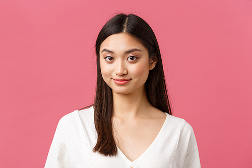 Beauty salon, haircare and skincare products advertisement concept. Close-up of young pretty asian woman smiling shy camera, standing pink background romantic. Copy space