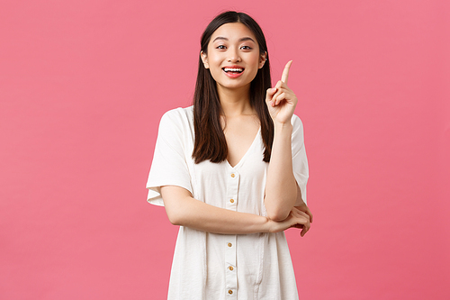 Beauty, people emotions and summer leisure concept. Excited good-looking asian girl in white dress have idea, raise index finger and suggest solution, tell her plan, pink background.