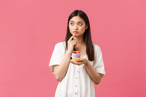 Food, cafe and restaurants, summer lifestyle concept. Thoughtful cute hesitant asian woman looking away doubtful, thinking about calories as staying on diet, tempting to eat delicious dessert.