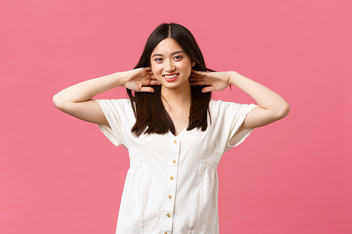 Beauty, people emotions and summer leisure and vacation concept. Sensual and tender asian woman bragging with hair haircut, show-off hair after haircare products or salon, pink background.