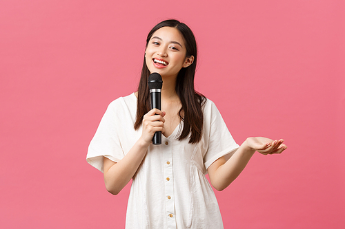 Leisure, people emotions and lifestyle concept. Charismatic pretty young asian girl making jokes, performing stand-up or give speech, singing karaoke with microphone, smiling camera.