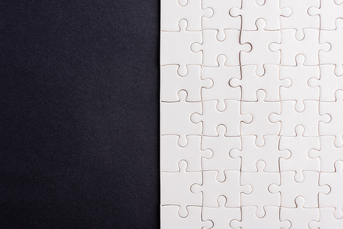 Top view flat lay of paper plain white jigsaw puzzle game texture on a black background, quiz calculation concept