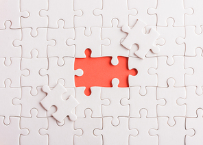 Top view flat lay of paper plain white jigsaw puzzle game texture last pieces for solve and place, studio shot on a red background, quiz calculation concept