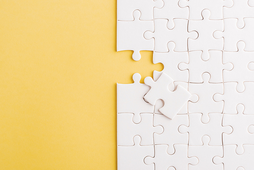 Top view flat lay of paper plain white jigsaw puzzle game texture last pieces for solve and place, studio shot on a yellow background, quiz calculation concept