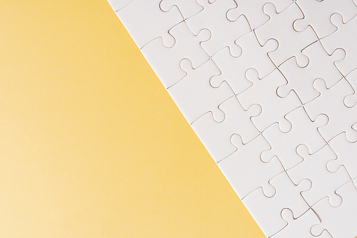 Top view flat lay of paper plain white jigsaw puzzle game texture on a yellow background, quiz calculation concept