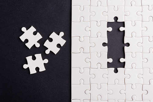 Top view flat lay of paper plain white jigsaw puzzle game texture last pieces for solve and place, studio shot on a black background, quiz calculation concept