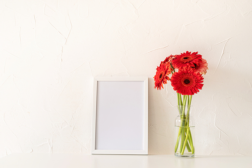 red gerbera flowers with a blank white frame on white background. Mock up design