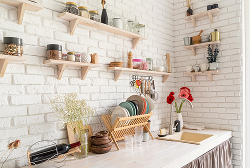 Rustic kitchen interior with white brick wall and white wooden shelves. Fresh gerbera flowers