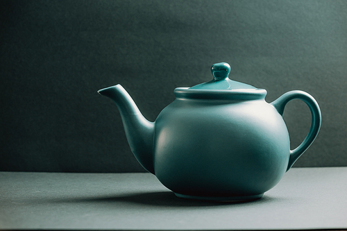 A blue teapot over a dark background
