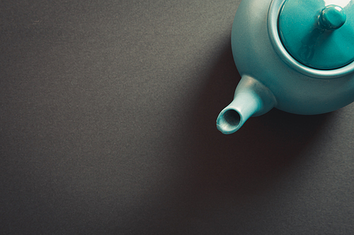 Top view of a blue vintage teapot showing from a corner over a dark background