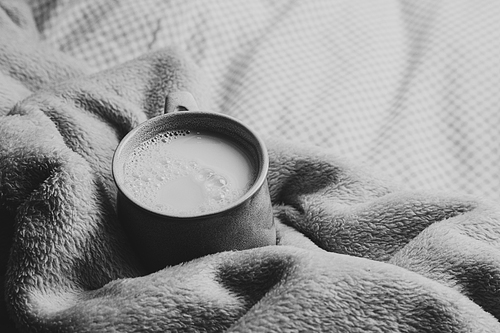 A cup of milk over a cozy blanket