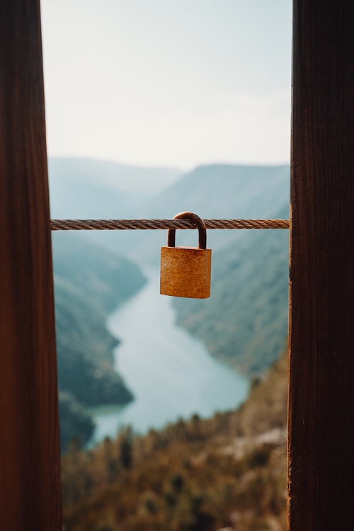 Single padlock hanging from a cord in front of a massive river with love and fidelity concept