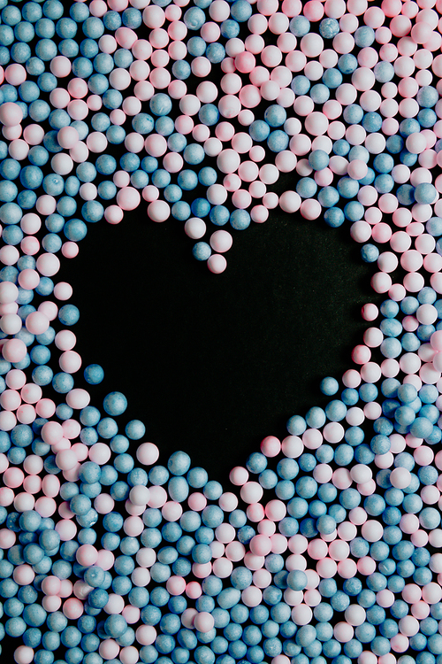 A black heart in the middle of pink and blue balloons love and equality concepts background