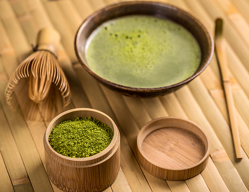 Green tea matcha in a bowl with whisk and spoon