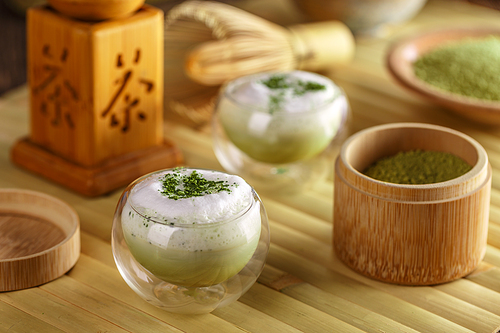 Glass of matcha green tea latte on bamboo tray