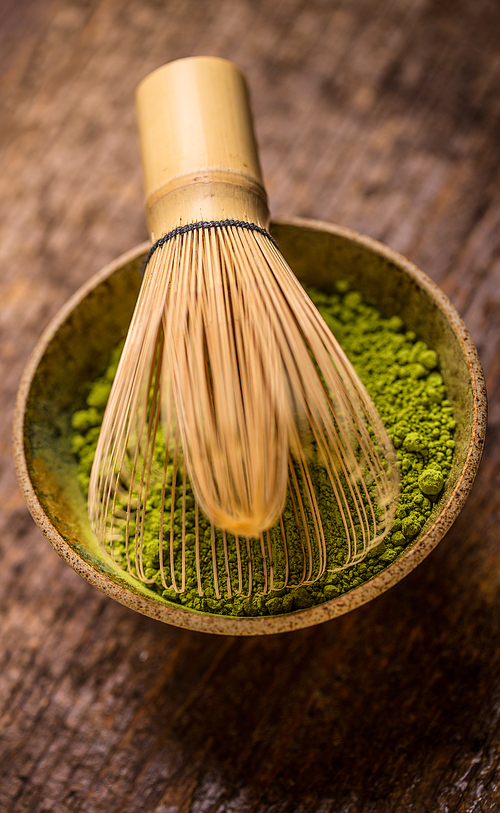 Raw organic green matcha tea in a bowl with whisk