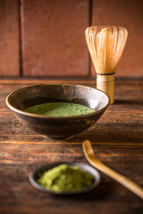 Green tea matcha in a bowl with whisk and spoon