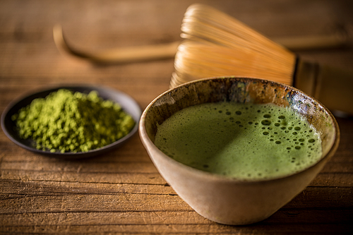 Matcha tea in bowl on wooden background