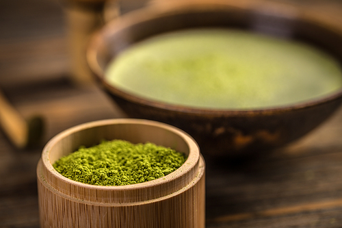 Organic green matcha tea powder in a bamboo bowl