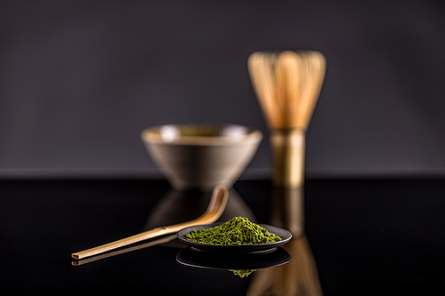 Powdered green tea in plate on black background