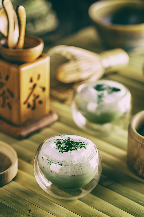 Still life with Japanese matcha accessories and matcha tea latte in small glass bowl