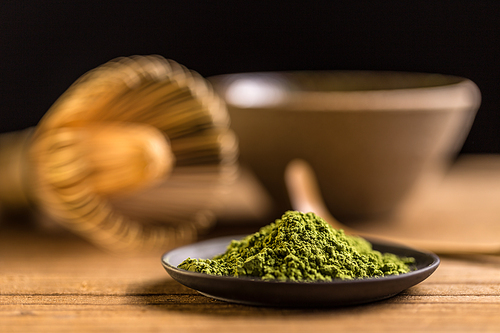 Macha green powder in a plate on wooden table